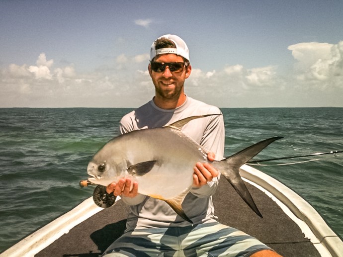 Angler Brett Bowen lands a beautiful permit off of Caye Caulker, Belize on a #6 tan merkin with orange legs and grizzly hackle claws. Photo courtesy of Brett Bowen.